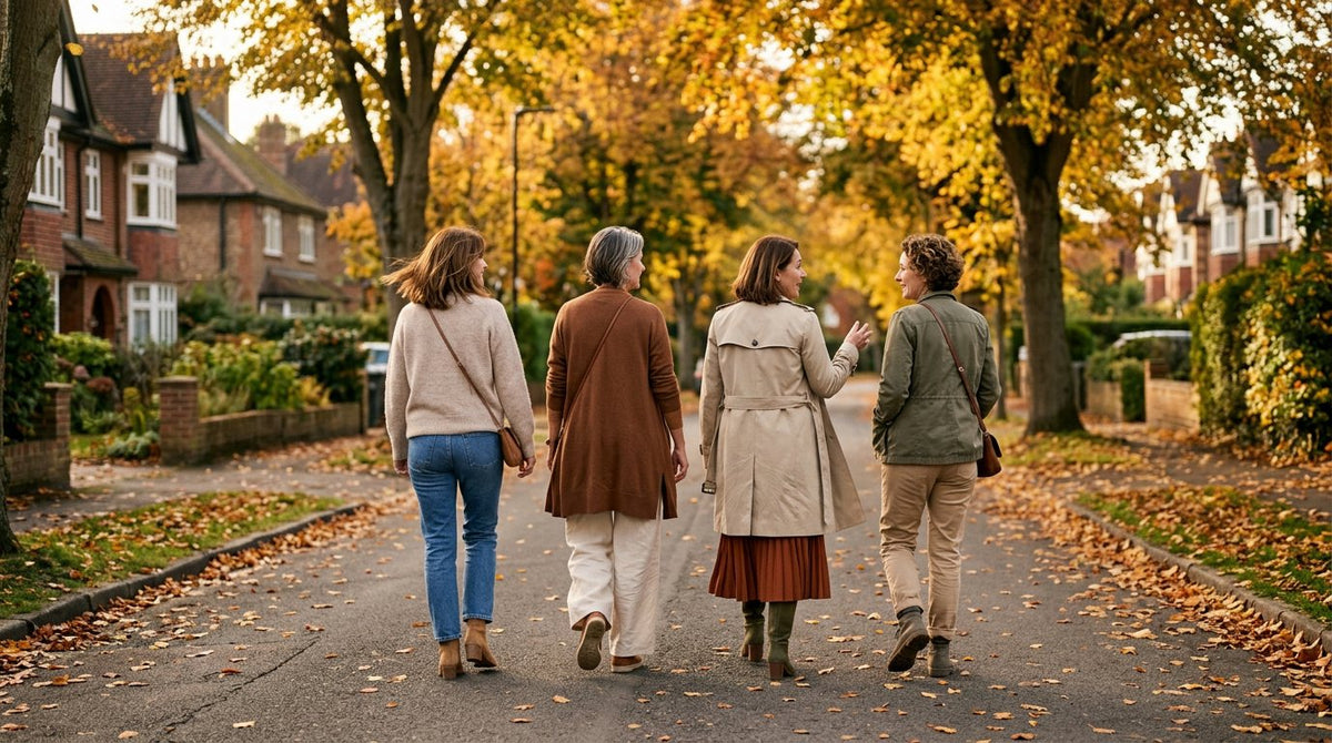 Four women walking on a tree-lined street in autumn, wearing knitwear, trousers and a midi skirt
